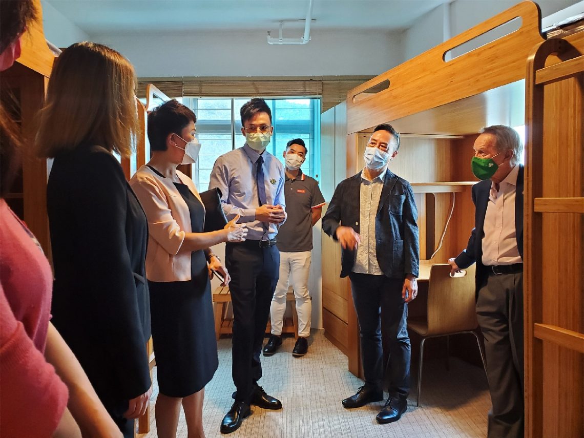 Mr Brandon Wu and Ms Esther Lee showcase a demo 3-student room at the Residential College to the Crown delegation.