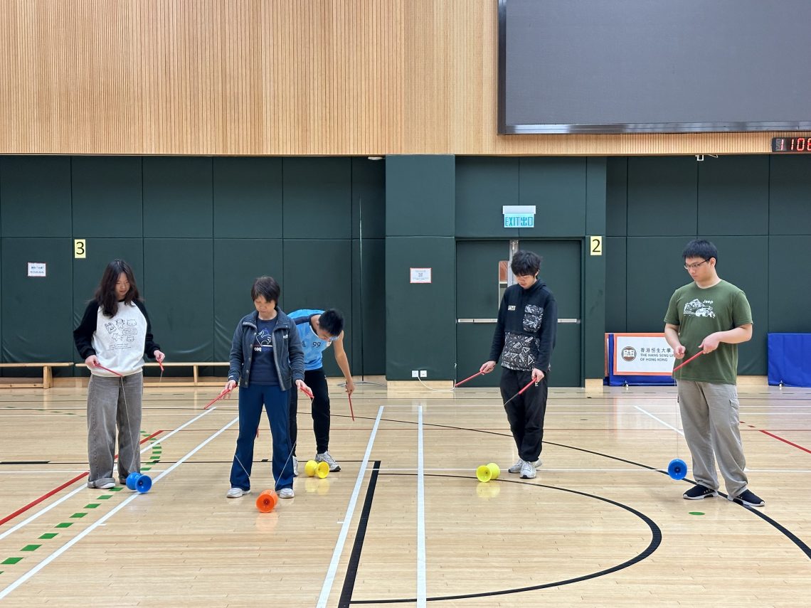 Students try to gain control over the diabolos on a string with handsticks.